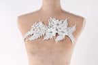 A mannequin torso with a decorative white lace flower piece on it.