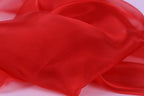 The image is a close-up of a red fabric, possibly silk or chiffon, with a soft, flowing texture.