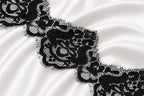 a close-up view of a delicate black lace pattern on a white fabric surface.