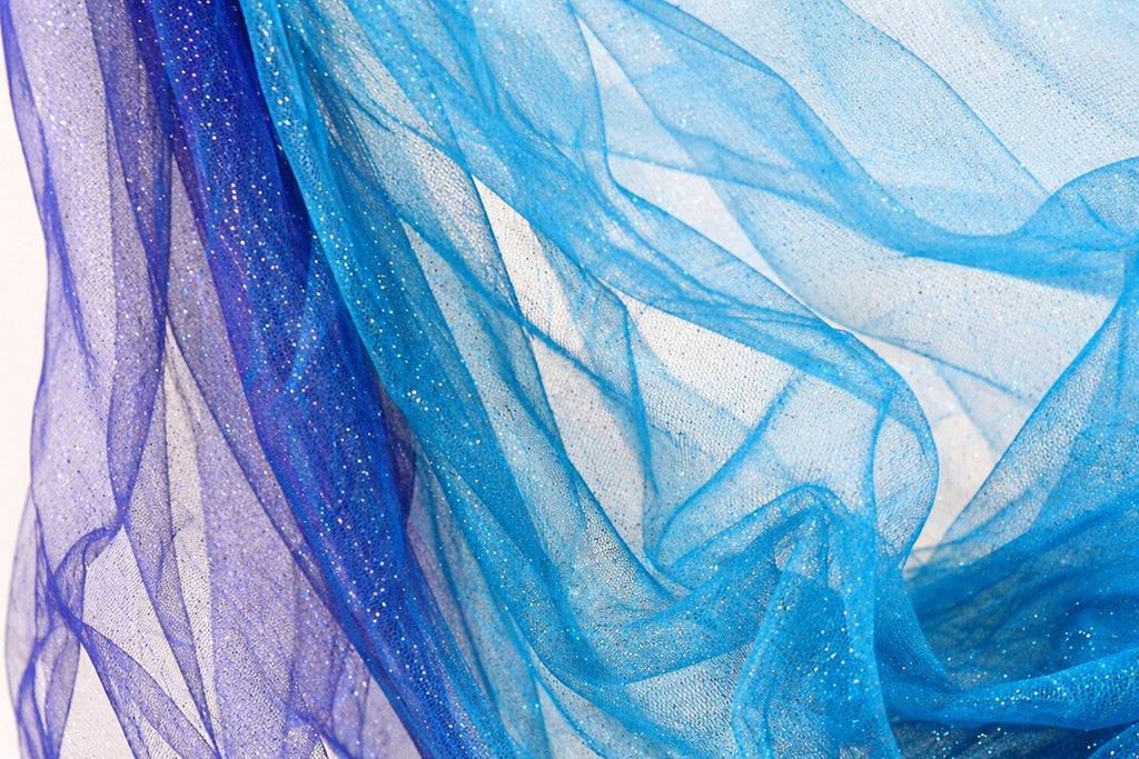 a close-up view of a piece of blue and purple fabric, with the fabric appearing to be made of sheer material. The fabric has a wavy texture, giving it a soft and flowing appearance. The colors of the fabric are vibrant and eye-catching, with the blue fabric appearing to be more dominant in the image.