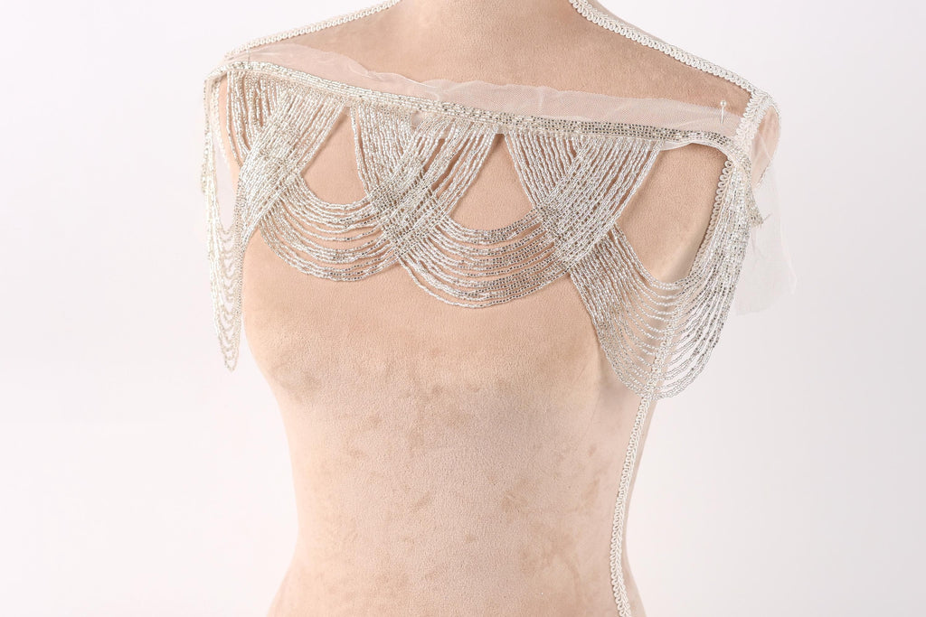 A mannequin wearing a beige dress with a decorative silver sequin overlay.