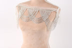 A mannequin wearing a beige dress with a decorative silver sequin overlay.