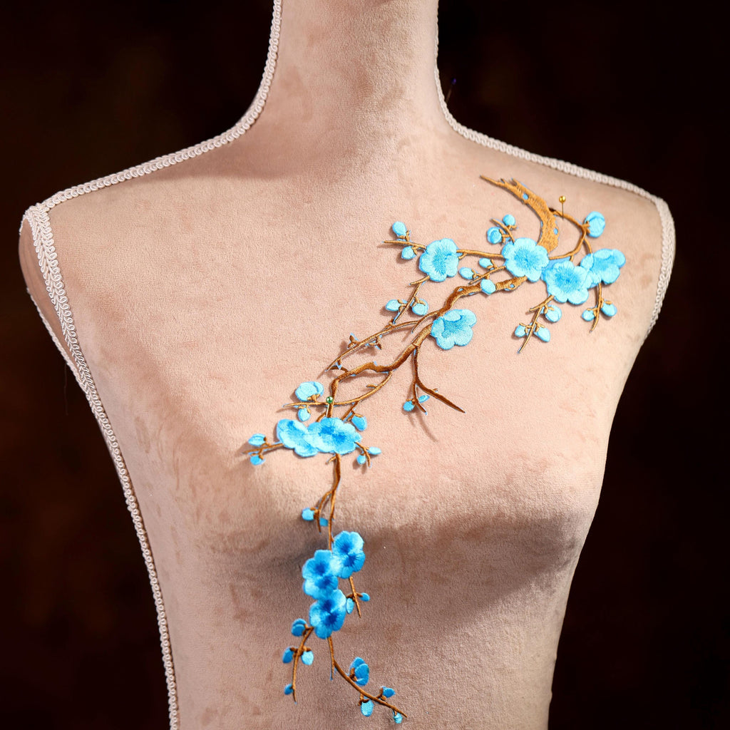 A mannequin with a floral design on its chest, featuring blue flowers and branches.