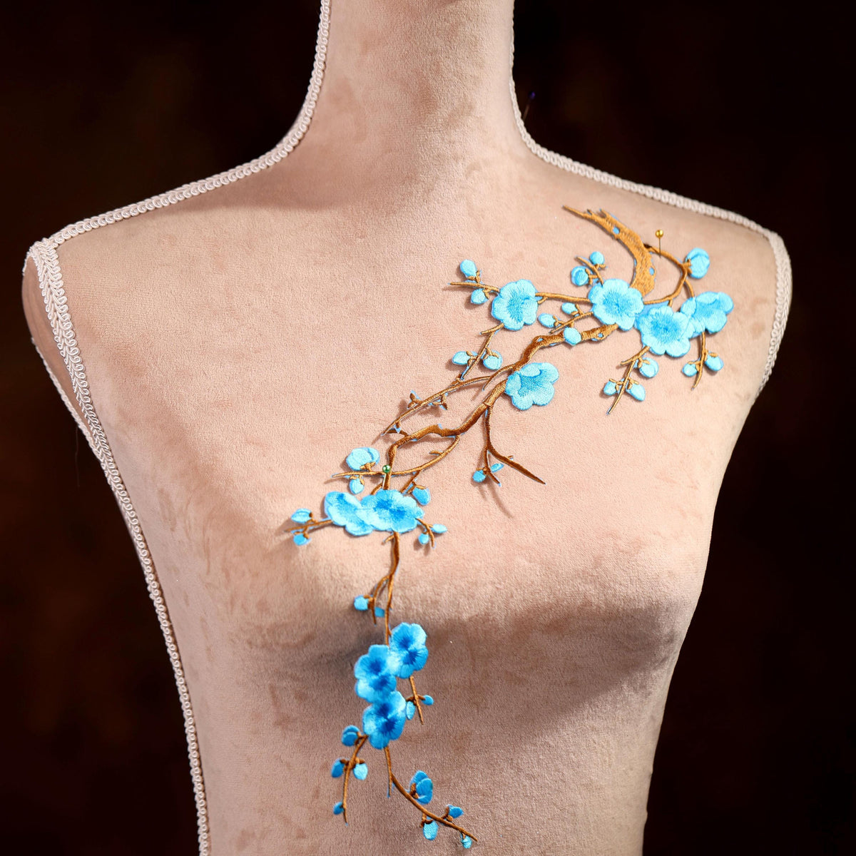 A mannequin with a floral design on its chest, featuring blue flowers and branches.