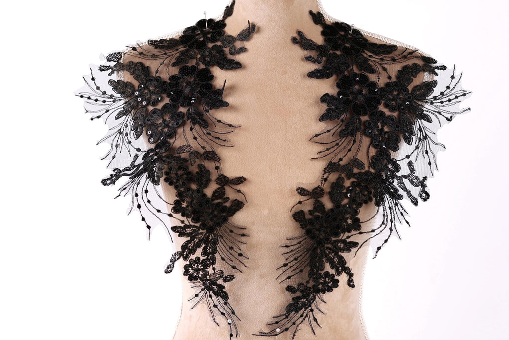 A mannequin wearing a black lace collar with intricate floral and leaf designs.