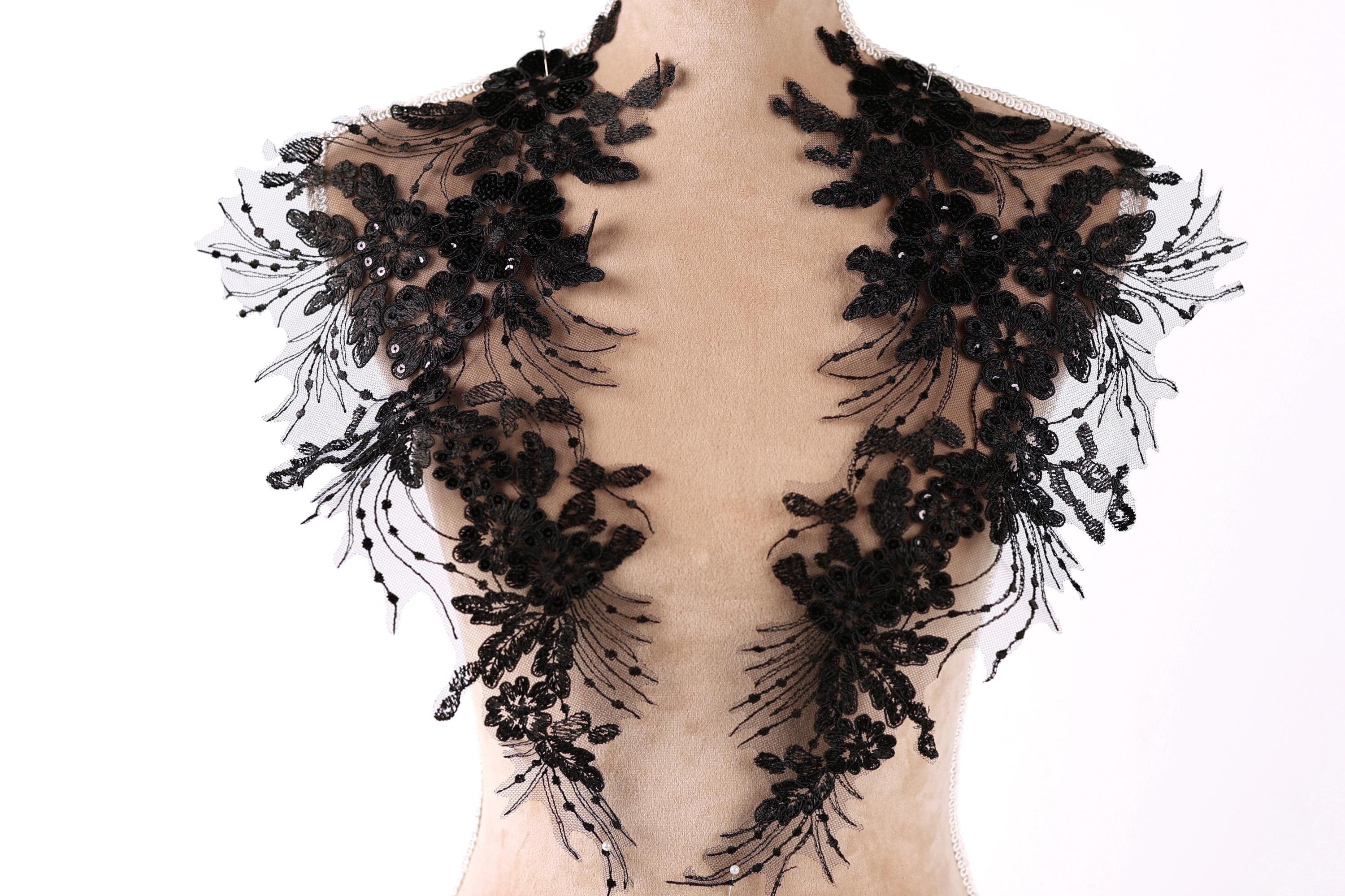 A mannequin wearing a black lace collar with intricate floral and leaf designs.