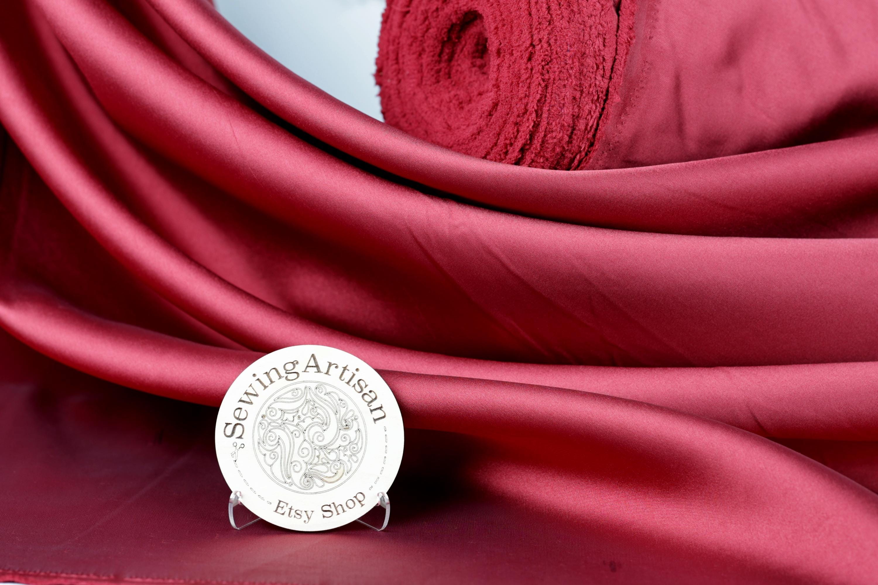 a red fabric with a white circular sign in the foreground, which reads "Sewing Artisan Ety Shop".