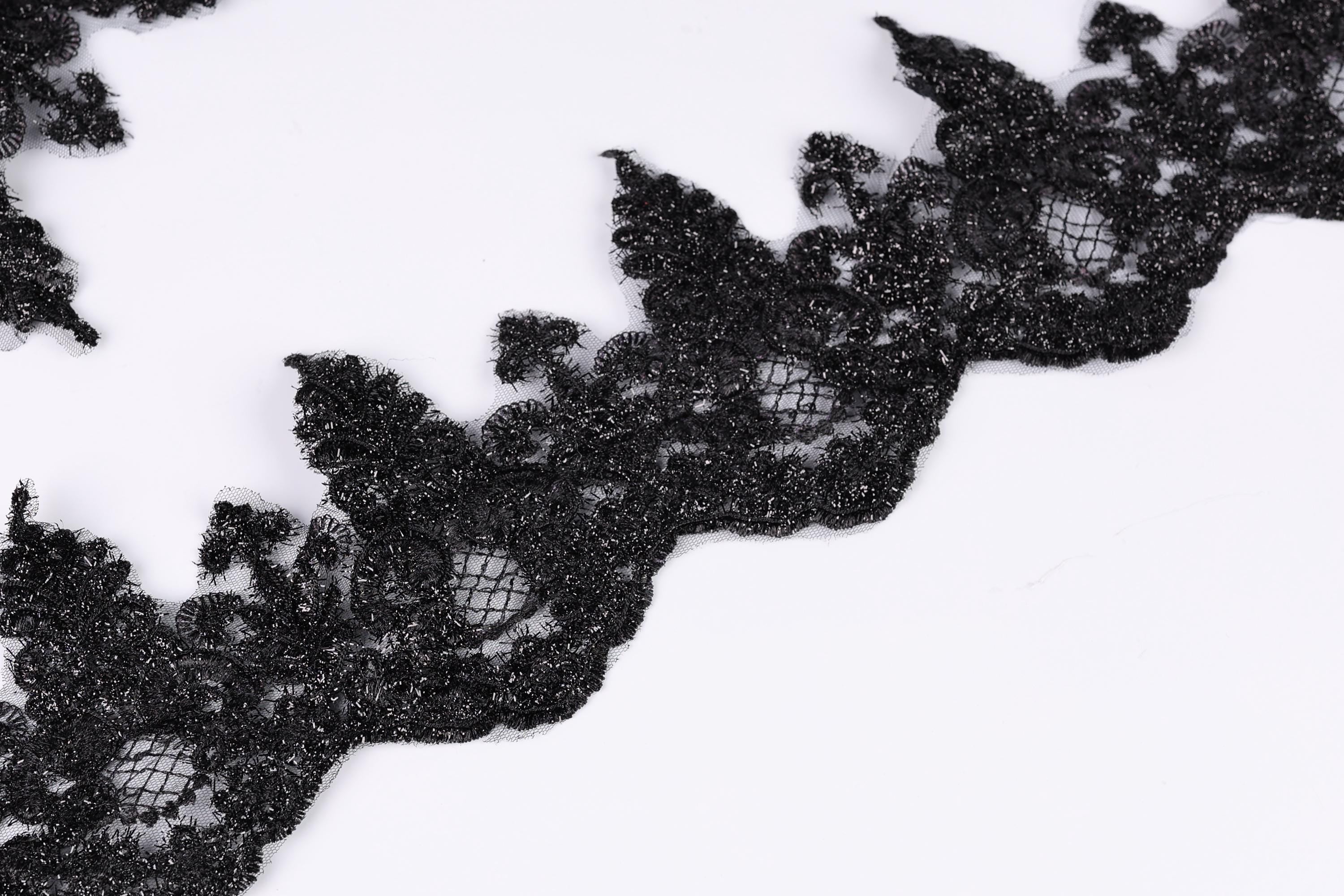 a close-up view of a black lace-like fabric with a textured, intricate design.