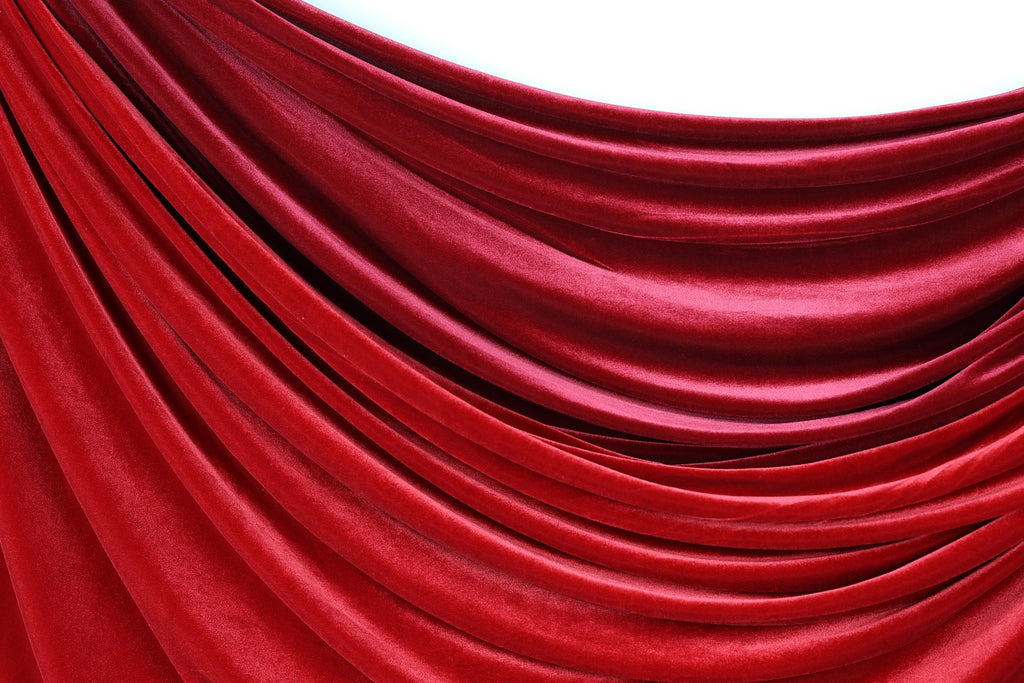 a close-up view of a red velvet curtain, with its folds and creases creating a textured and flowing appearance.