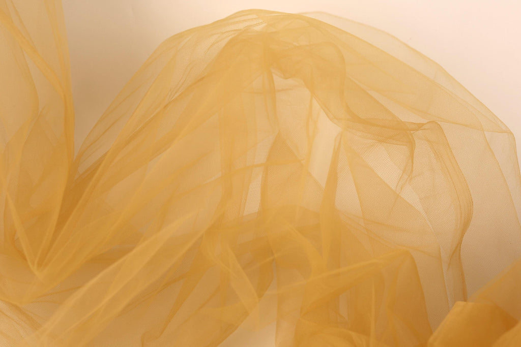 The image is a close-up of a yellow, flowing fabric, possibly a tulle or chiffon, with a soft, delicate texture.