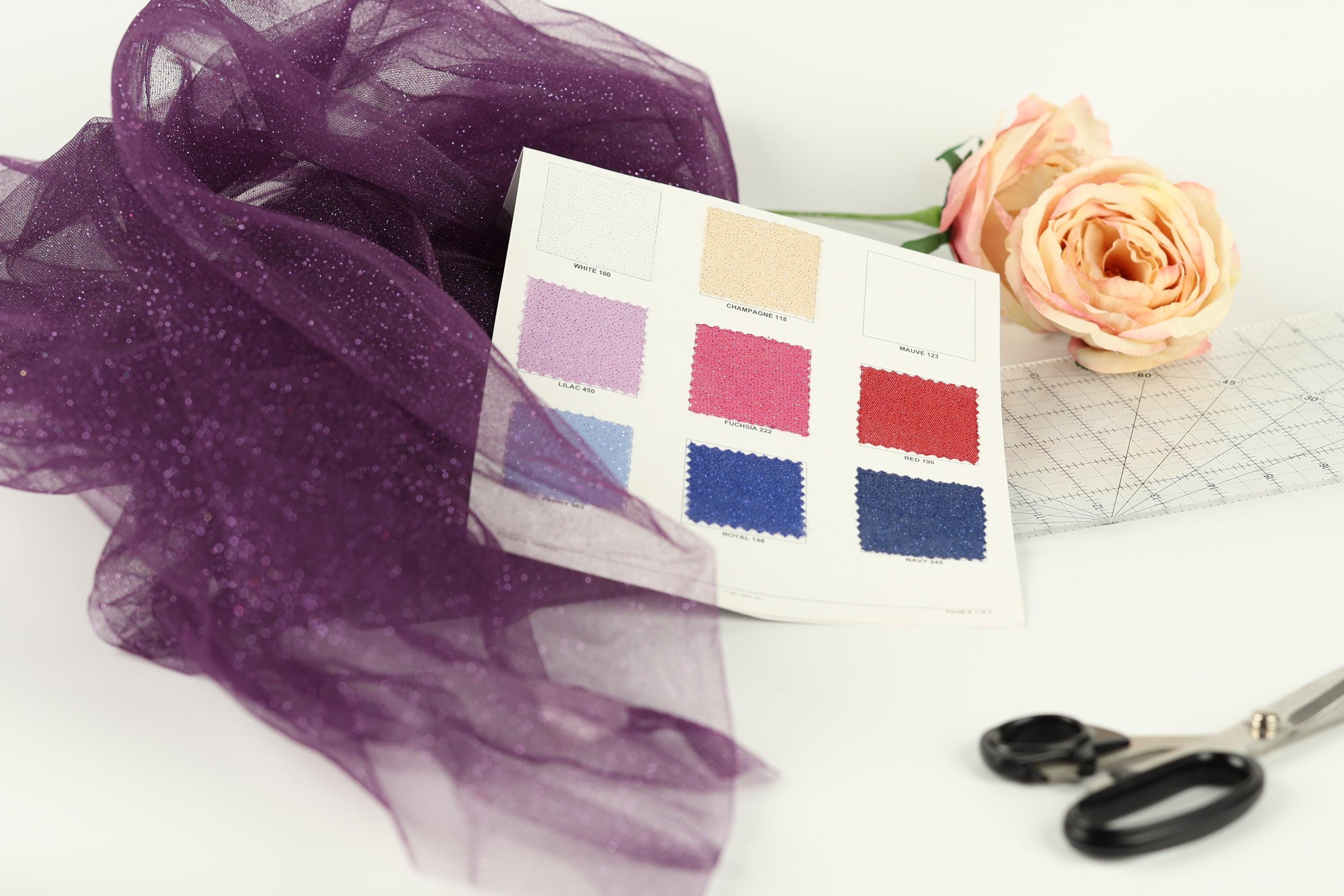 a variety of fabric swatches, a pair of scissors, and a rose, all arranged on a white background.