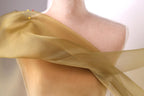 A close-up view of a mannequin wearing a gold-colored fabric draped over its body.
