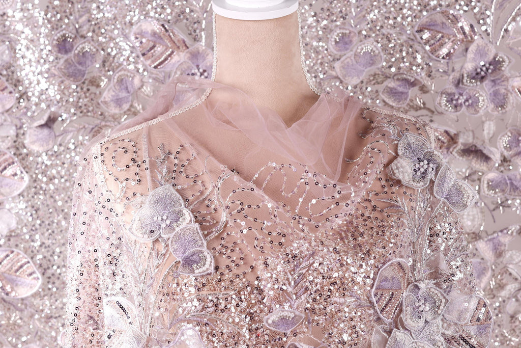 a mannequin wearing a pink and white sequined dress with a sheer, tulle-like fabric draped over it.