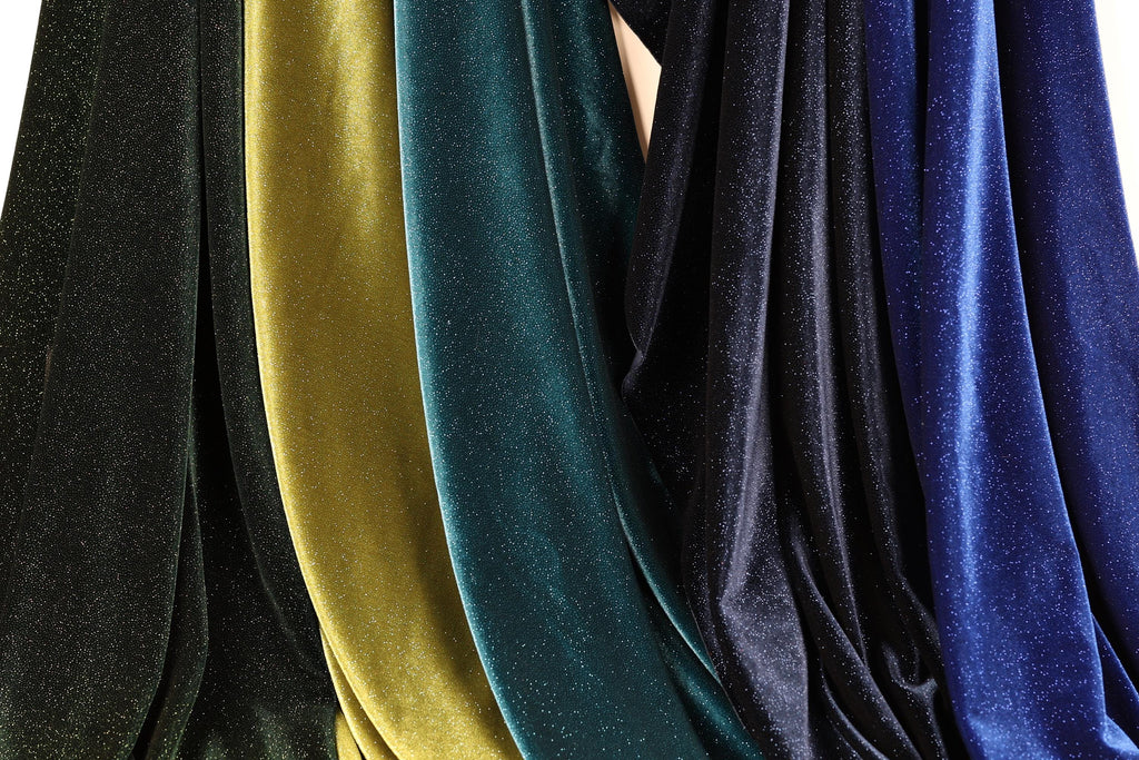 a collection of colorful velvet fabric, with various shades of green, blue, and black. The fabric appears to be made of a shiny, glittery material, giving it a vibrant and eye-catching appearance.