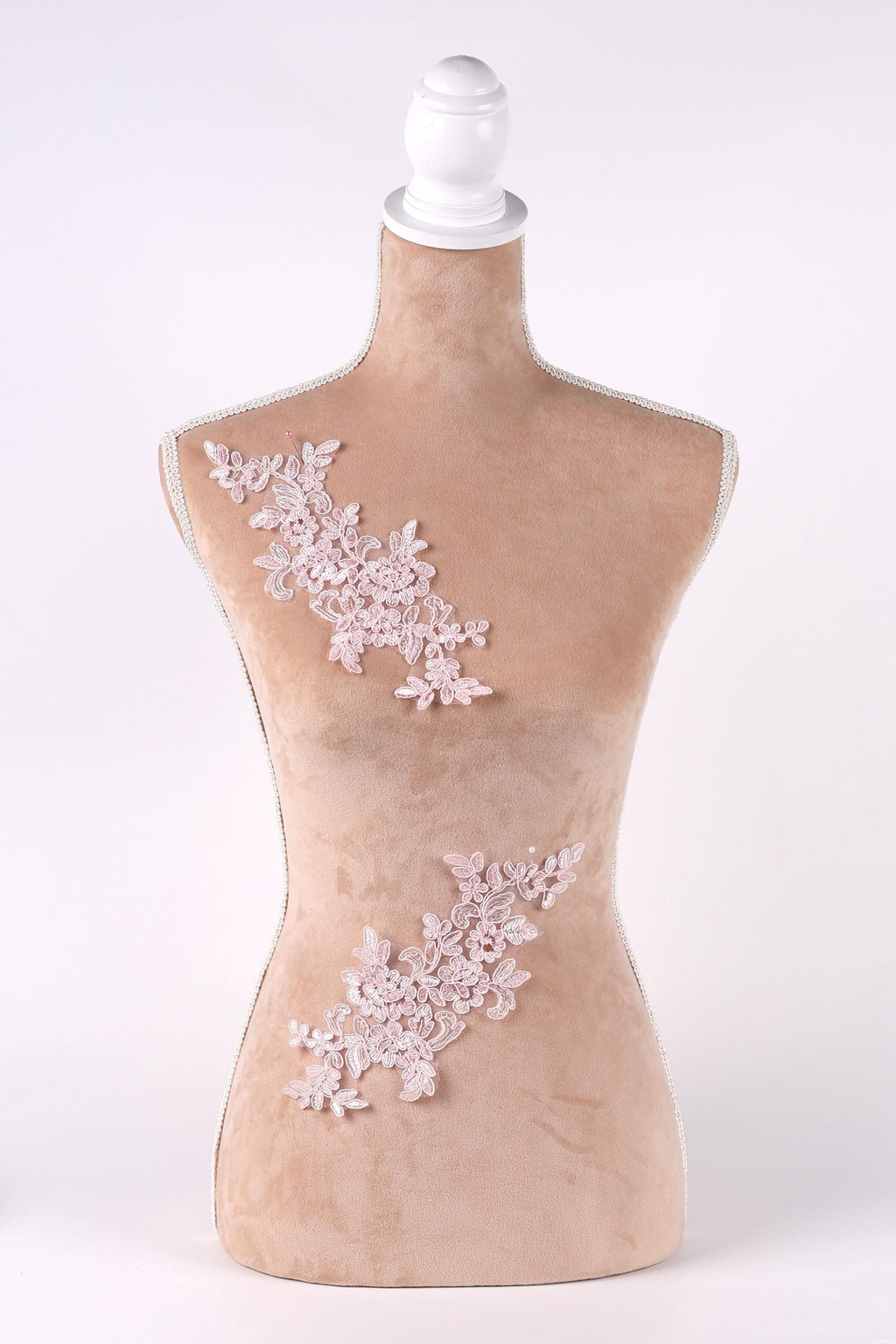 A mannequin with a beige body and a white headpiece, adorned with delicate pink floral embroidery on the bust and waist areas.