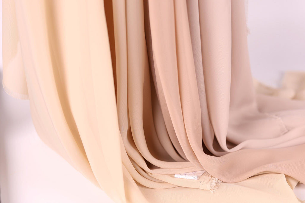 A close-up view of a soft, light-colored fabric, possibly a sheer or sheer-like material, with a delicate texture.