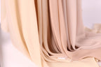 A close-up view of a soft, light-colored fabric, possibly a sheer or sheer-like material, with a delicate texture.