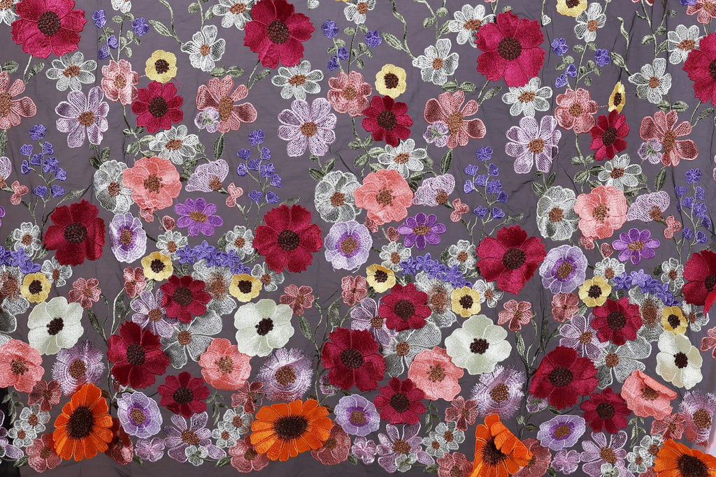 a vibrant and colorful floral pattern, with a variety of flowers in shades of red, pink, white, and purple. The flowers are intricately embroidered or sewn onto a fabric, creating a visually striking and detailed design.