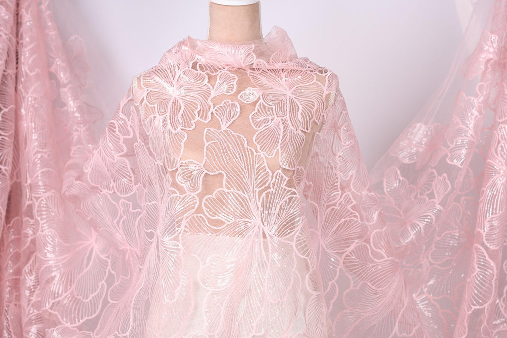 A mannequin wearing a pink lace dress with a floral pattern.