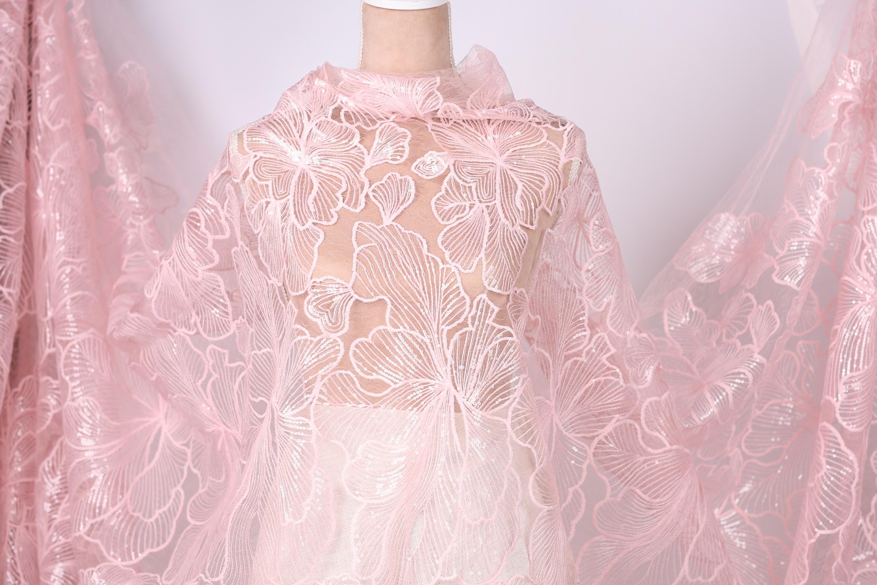A mannequin wearing a pink lace dress with a floral pattern.
