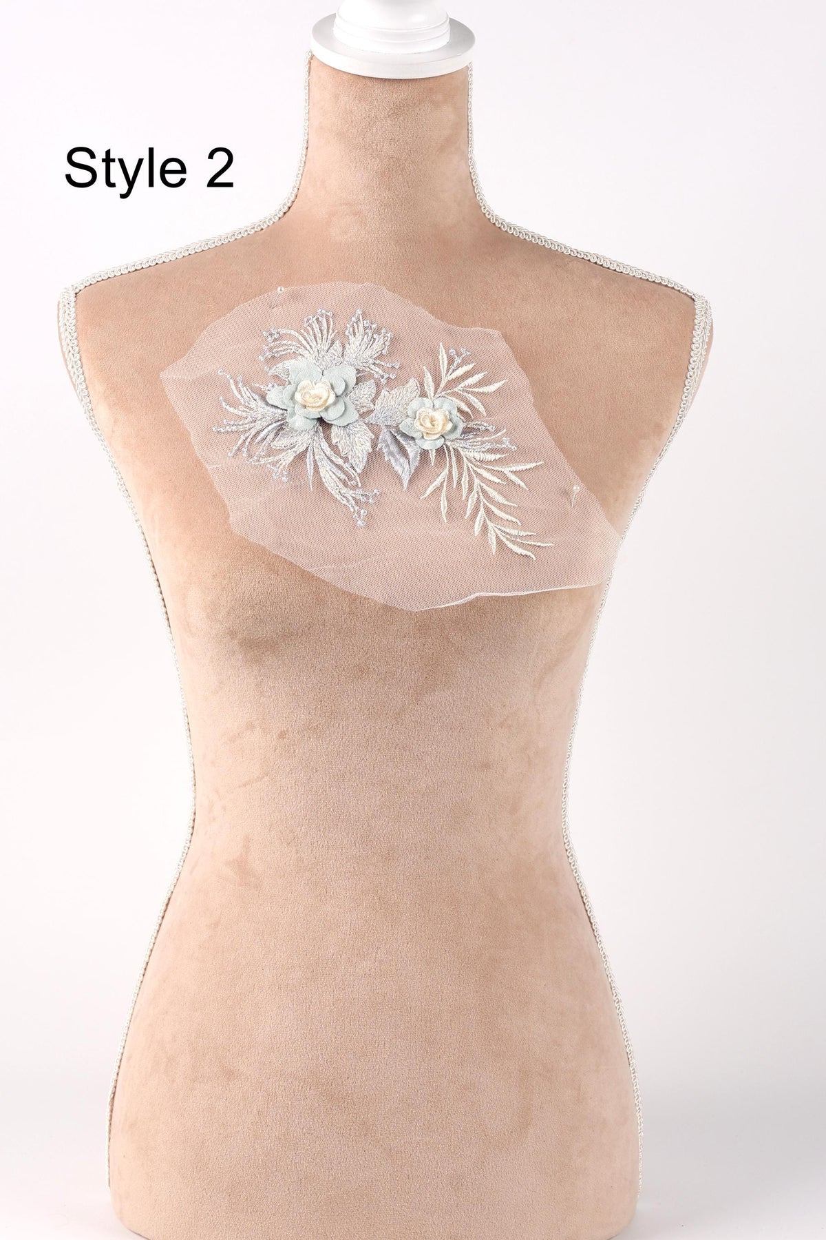 A mannequin with a floral design on its bust, featuring two white flowers and green leaves.