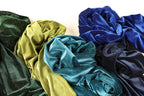 a variety of colorful, shiny fabrics, including blue, green, and yellow, arranged together.
