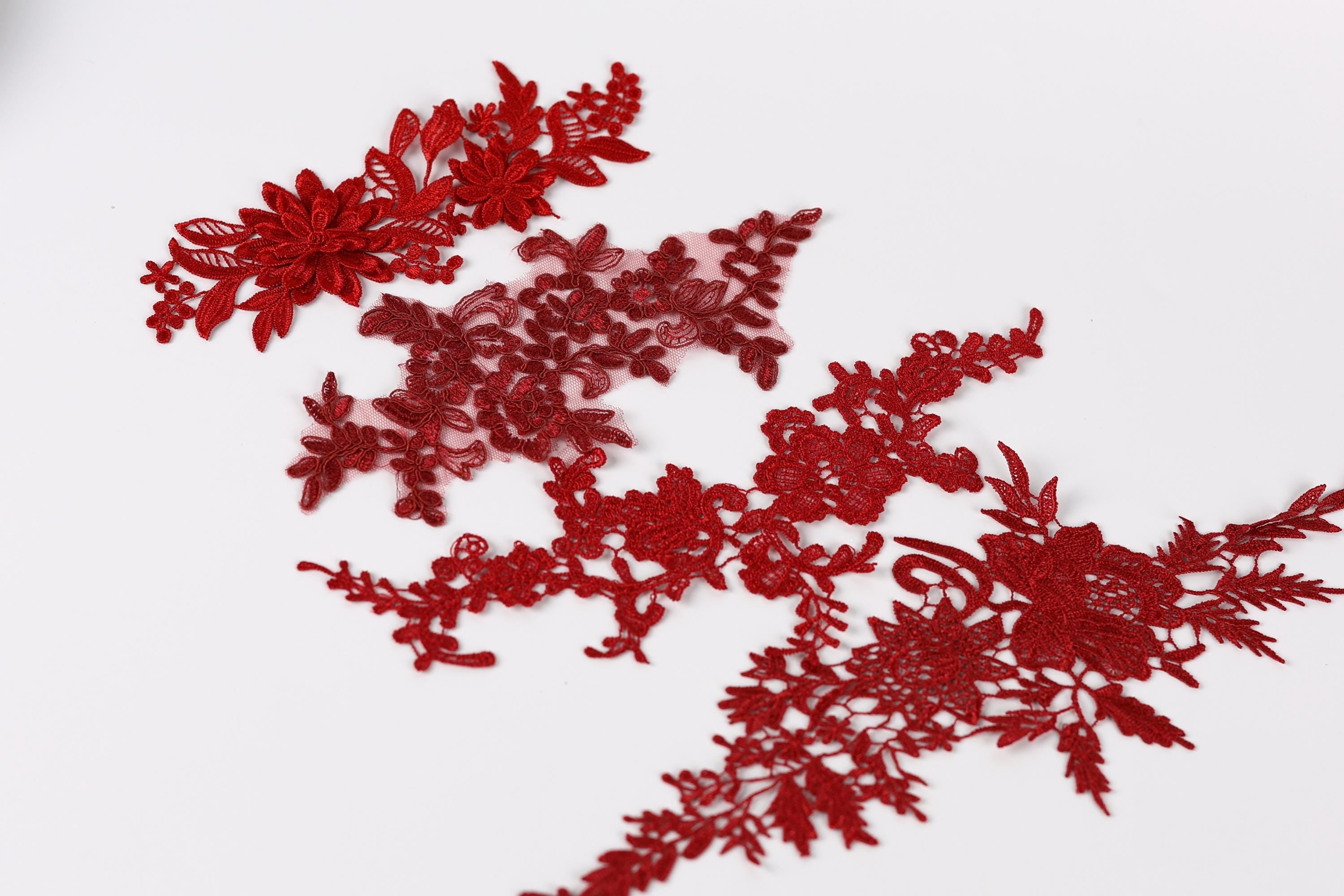 a collection of red floral embroidery pieces, including a large flower-shaped piece and smaller floral pieces, arranged on a white background.