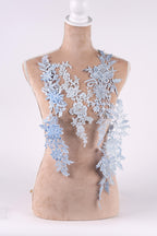 A mannequin wearing a dress with delicate blue lace appliques.