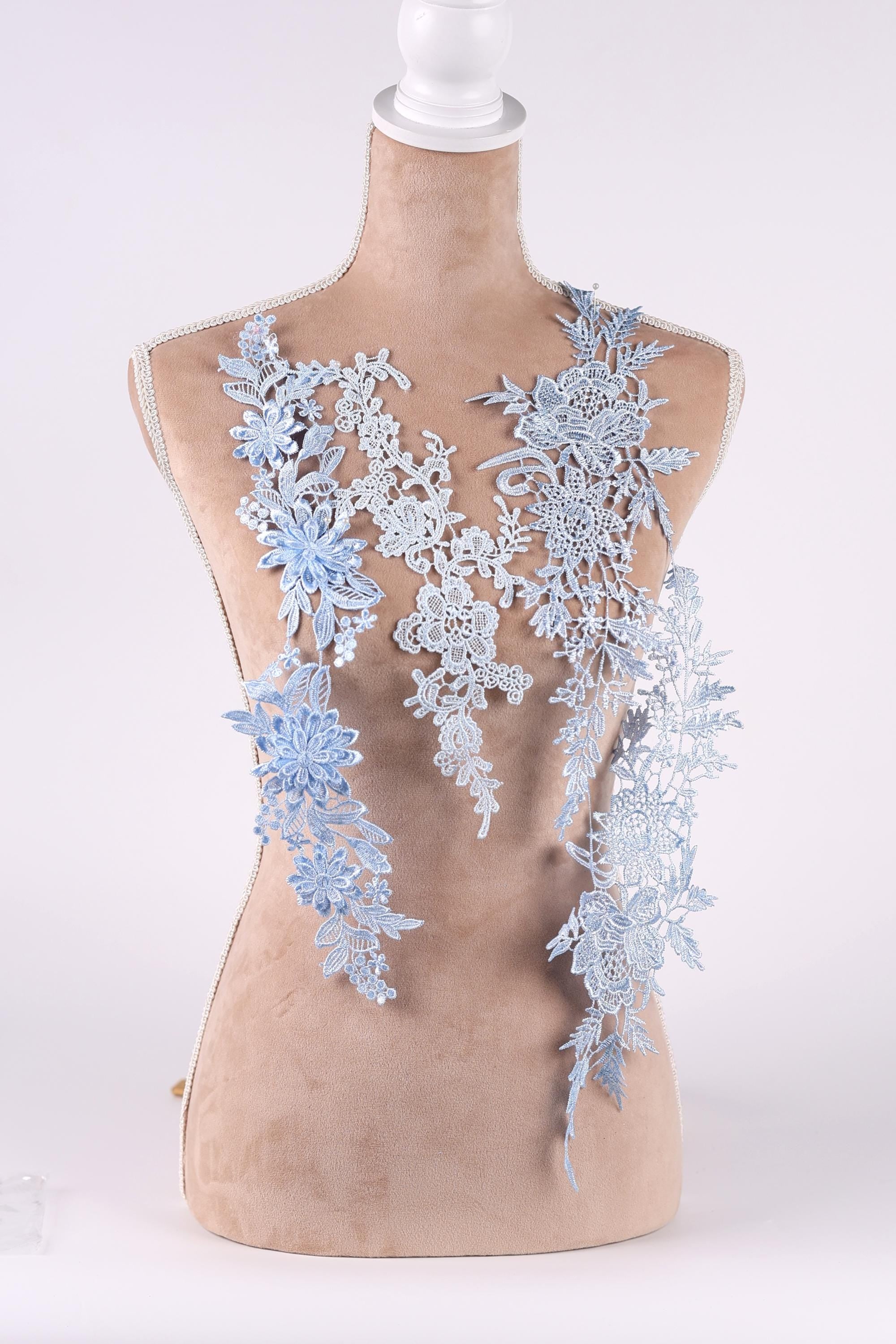 A mannequin wearing a dress with delicate blue lace appliques.