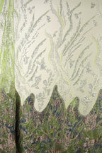 a close-up view of a fabric with a floral pattern in shades of green and white. The fabric appears to be made of a shiny, metallic material, giving it a metallic, sparkly appearance. The pattern consists of various shapes and lines, creating a visually striking and intricate design.