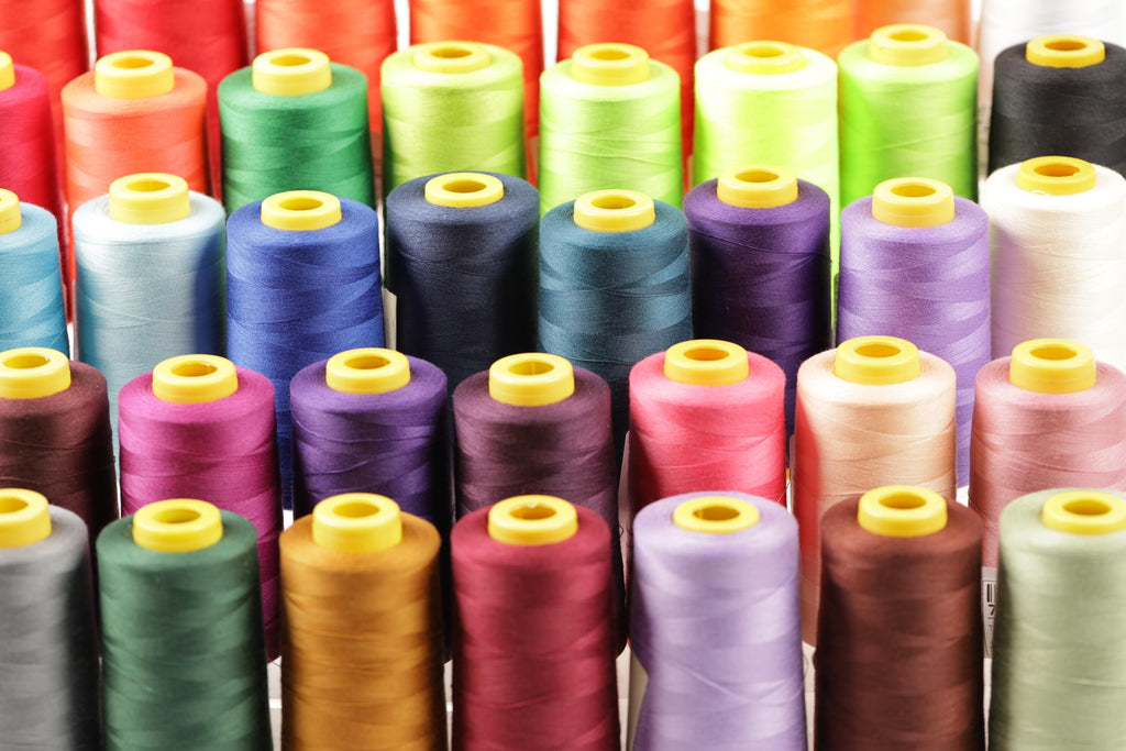 A close-up image of a collection of colorful spools of thread, with each spool featuring a yellow cap.