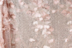 a close-up view of a fabric with a delicate floral pattern, including pink and white flowers and leaves. The fabric appears to be made of a shiny, sequined material, giving it a sparkly and elegant appearance.