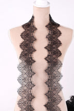 A mannequin wearing a black lace scarf with a zigzag pattern.