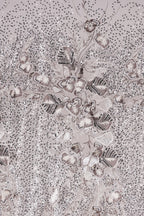 The image is a close-up of a fabric with a floral pattern, featuring a variety of small, intricately designed flowers and leaves. The fabric appears to be made of a shiny, metallic material, giving it a metallic, glittery appearance. The pattern is detailed and visually striking, with the flowers and leaves arranged in a way that creates a sense of depth and complexity.