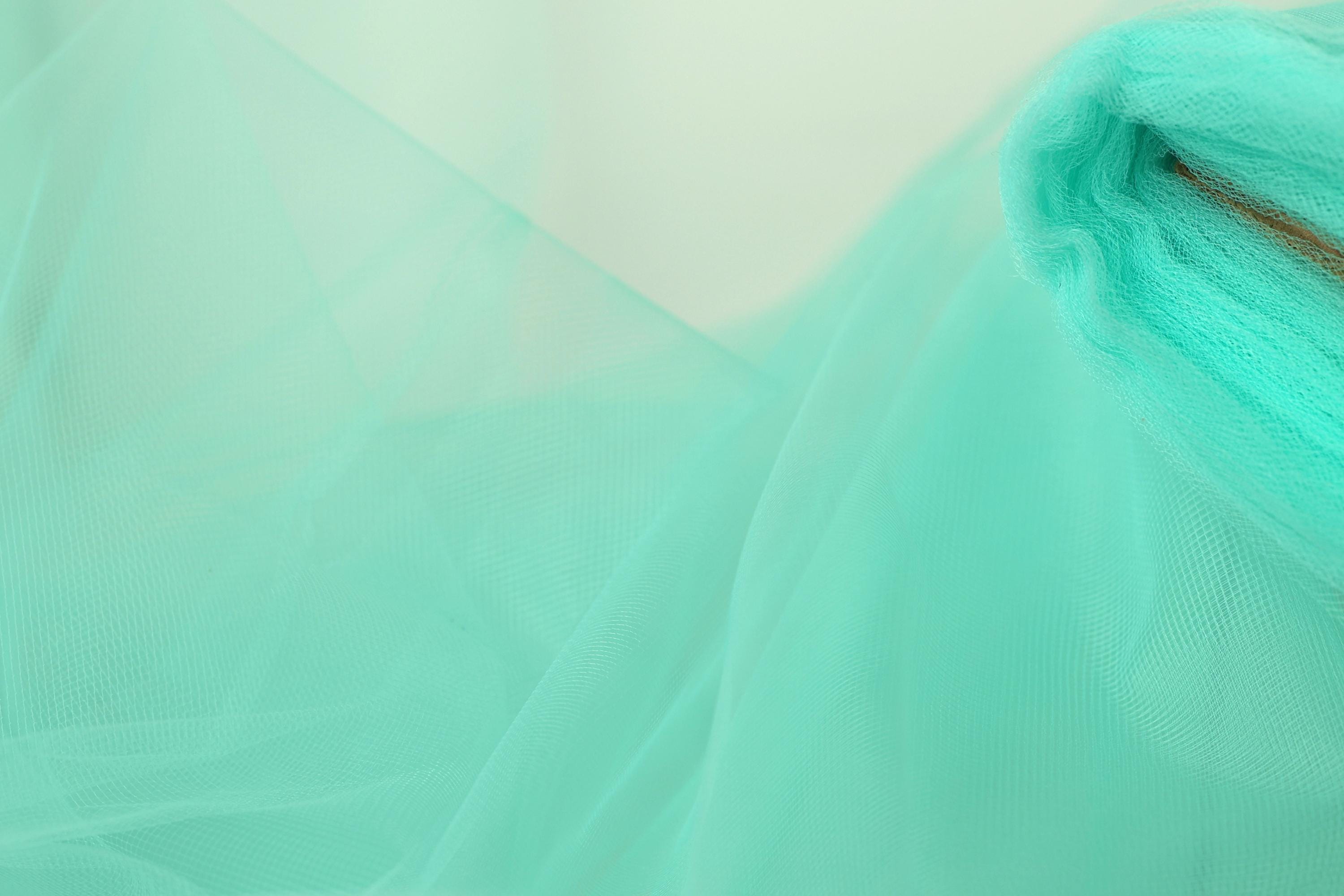 A close-up view of a light blue, sheer fabric, possibly tulle, with a subtle texture.