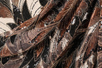 The image is a close-up of a fabric with a complex, intricate pattern of brown, black, and white sequins and beads. The pattern appears to be a mix of floral and geometric designs, creating a visually striking and detailed appearance.