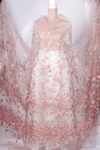 A mannequin wearing a white dress with a sheer, floral-patterned cape draped over it.