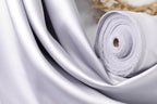 A close-up view of a white satin fabric, possibly silk, with a rolled-up end visible.
