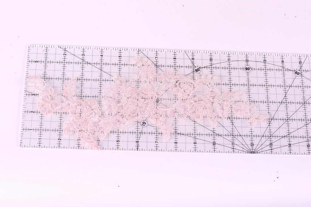 a clear ruler with a pink lace pattern on it, placed on a white surface.