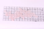 a clear ruler with a pink lace pattern on it, placed on a white surface.