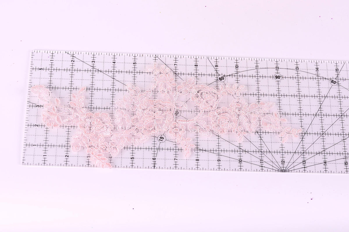 a clear ruler with a pink lace pattern on it, placed on a white surface.