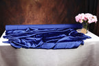 a table with a blue satin fabric draped over it, and a vase of pink flowers placed on the table.