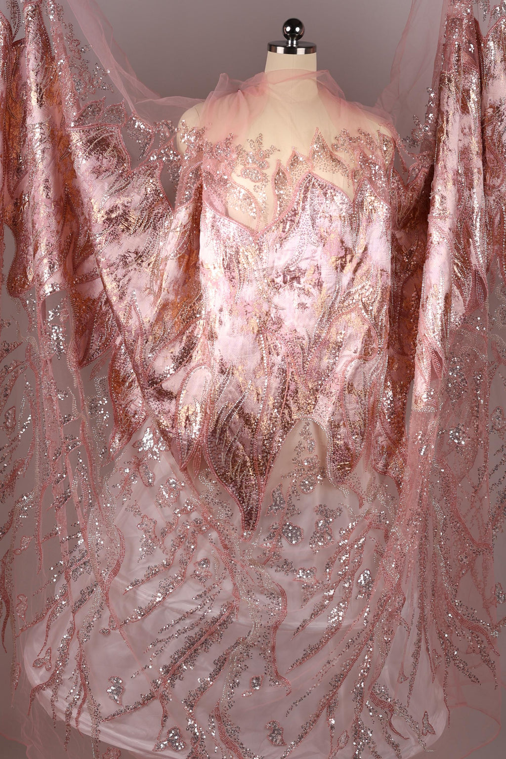 a pink and gold dress with intricate lace and sequin details, creating a visually striking and elegant garment.