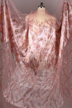 a pink and gold dress with intricate lace and sequin details, creating a visually striking and elegant garment.