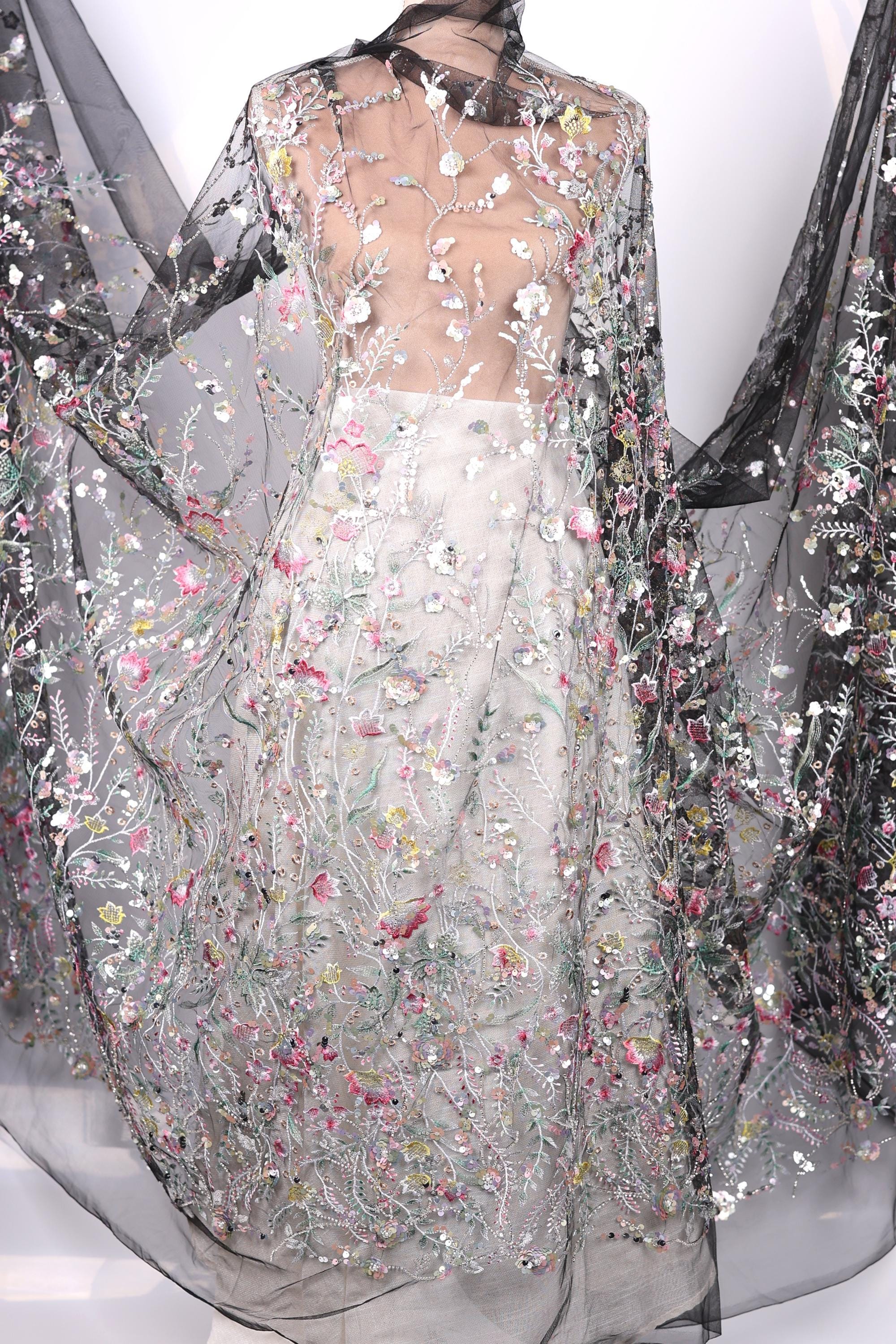 a dress with a sheer, floral-patterned fabric. The dress appears to be made of sheer material, giving it a delicate and elegant appearance. The dress is adorned with a variety of flowers and leaves, creating a visually striking and intricate design. The dress is displayed on a mannequin, showcasing its unique and eye-catching design.