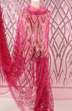 a mannequin wearing a pink sequin dress with a sheer overlay. The dress has a long, flowing skirt and is adorned with a pattern of pink sequins. The background is a pink and white patterned fabric, which complements the overall color scheme of the dress.