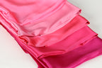 A close-up image of a stack of fabric swatches in various shades of pink, ranging from a soft, pastel hue to a more vibrant, fiery tone.