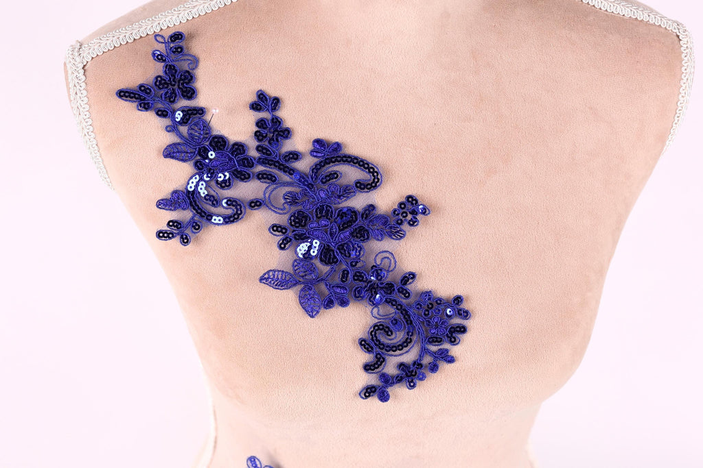 a mannequin torso with a decorative blue sequin floral piece attached to it.