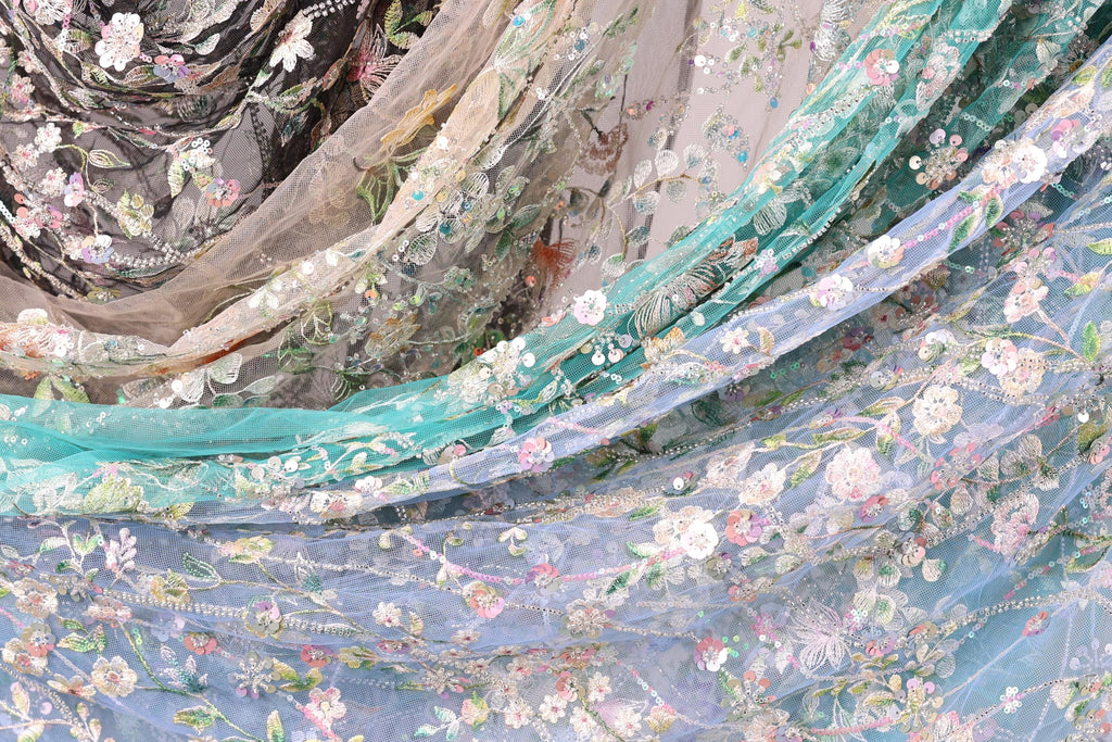 The image is a close-up of a fabric with a floral pattern, featuring various shades of blue, green, and white.