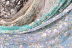 The image is a close-up of a fabric with a floral pattern, featuring various shades of blue, green, and white.